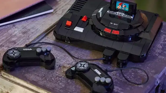 Miniatura LEGO do console Sega Mega Drive com luz de LED acesa, um cartucho de jogo inserido, e um controle com fio, ao lado de uma base que simula o console real.