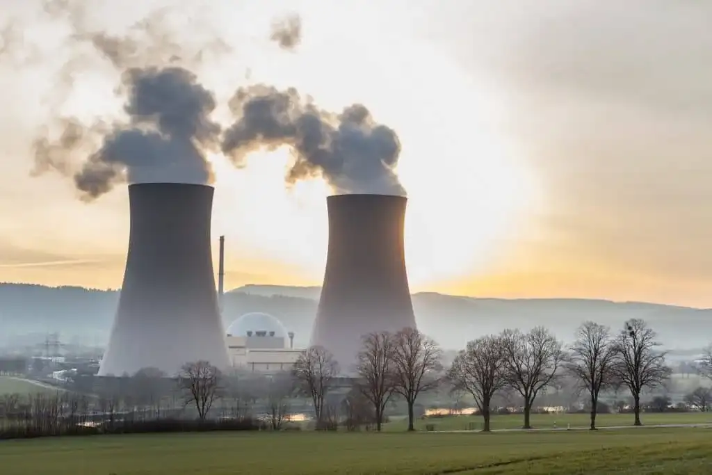 Imagem de uma usina de energia nuclear com torres de resfriamento, simbolizando a aposta das big techs em energia atômica para IA.