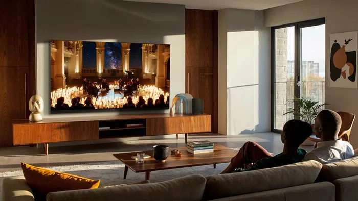 Imagem de um aparelho de ar-condicionado moderno e uma TV de tela grande e fina com cores vibrantes, simbolizando a linha de produtos premium da TCL para 2026.