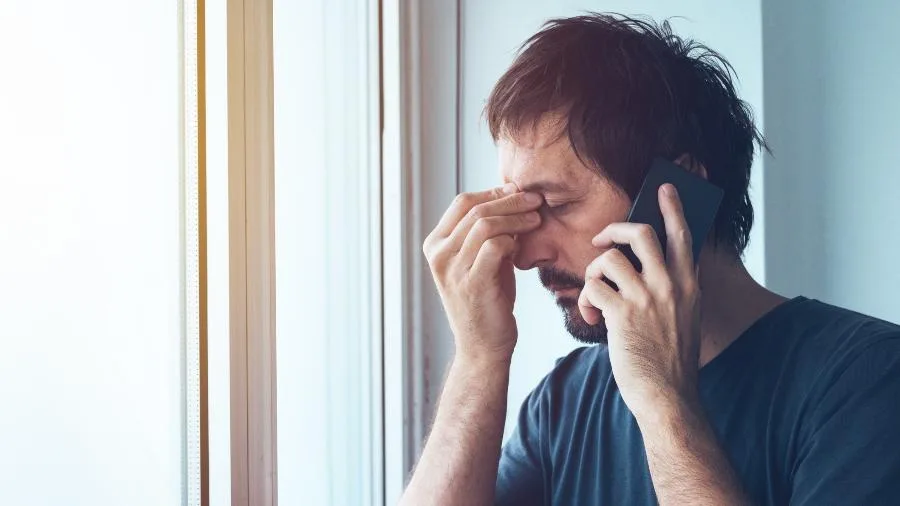Mão segurando um celular com o visor piscando, simbolizando as chamadas incessantes de telemarketing que irritam milhões de brasileiros diariamente.