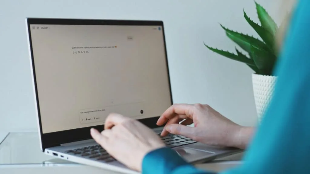 Uma pessoa olhando para uma tela de notebook com a interface do ChatGPT aberta, em um ambiente de escritório.