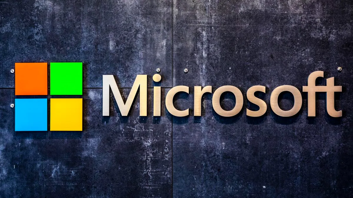 Jovens e instrutores em uma sala de aula de tecnologia, com computadores e o logotipo da Microsoft ao fundo, participando do programa COLAI.