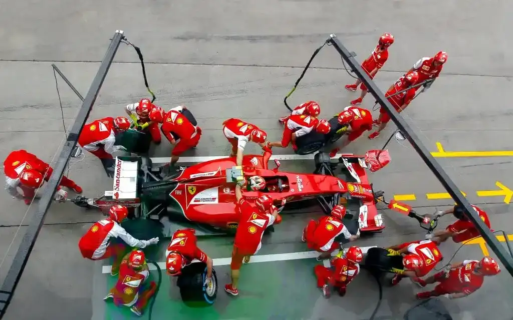 Equipe de Fórmula 1 em pit stop com carro de corrida, destacando a transição para combustíveis sintéticos.