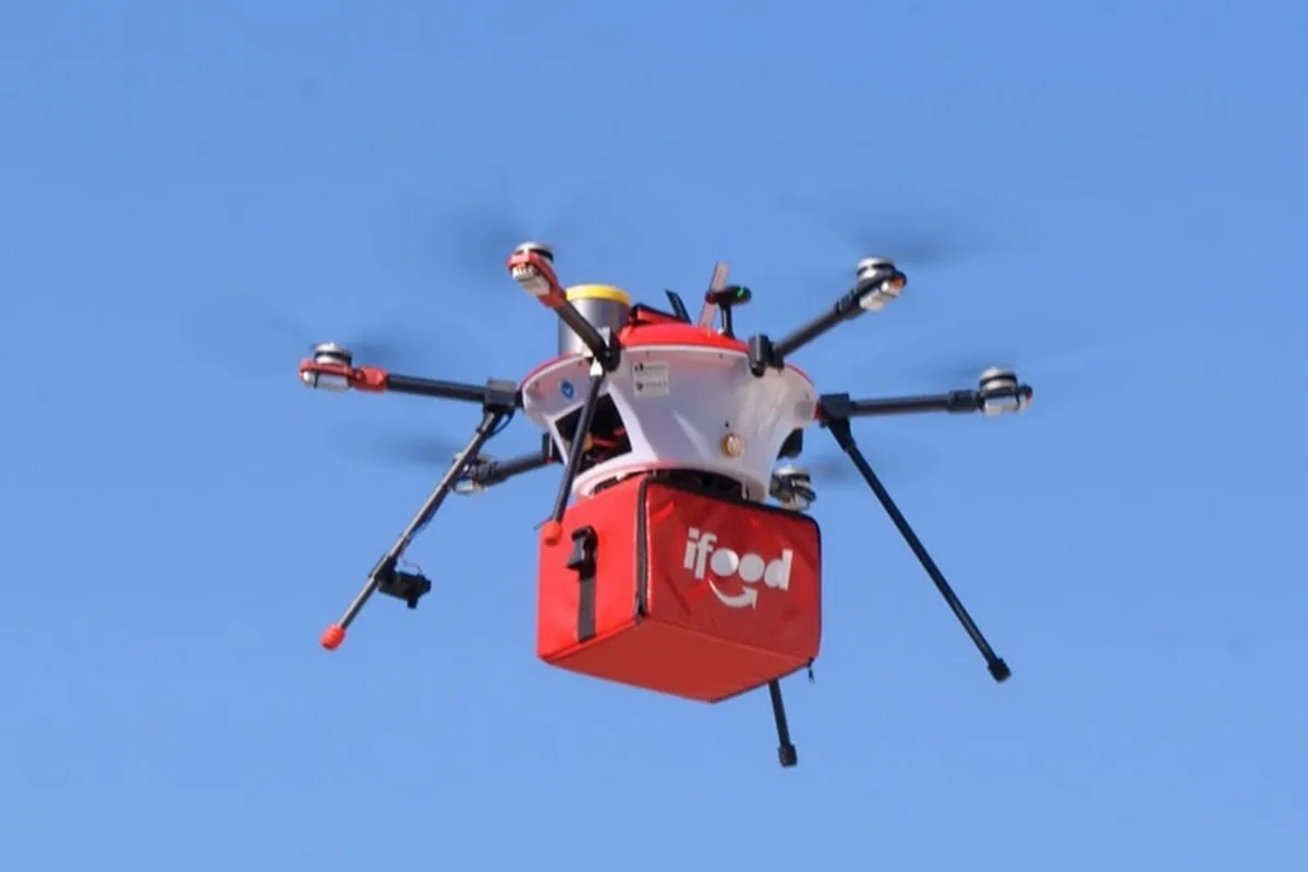 Drone do iFood realizando uma entrega em uma cidade brasileira, demonstrando a tecnologia de delivery aéreo.