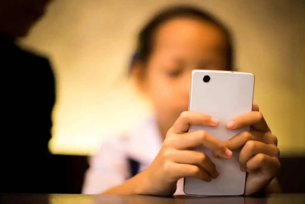 Criança usando um smartphone e logos de redes sociais em uma tela de celular