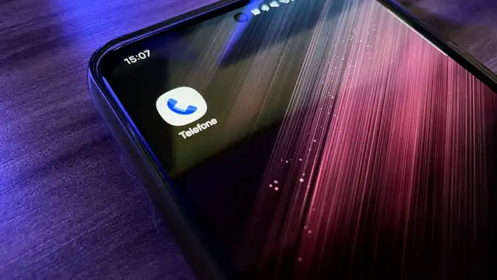 Smartphone Android exibindo tela de chamada com aviso de possível fraude. Um robô Android verde estilizado aparece ao lado do celular.