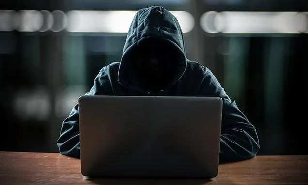 Capa de matéria sobre cibersegurança: imagem ilustrativa de um homem jovem, com capuz e fones de ouvido, mexendo intensamente em um notebook, com códigos de programação ao fundo e um cadeado digital, representando o ato de hackear ou lidar com segurança da informação.
