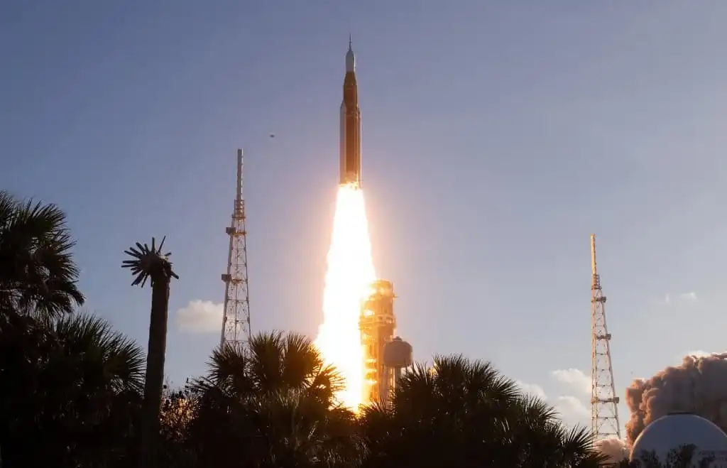 Lançamento do foguete SLS com a cápsula Orion para a missão Artemis 2 da NASA, com a Terra ao fundo.