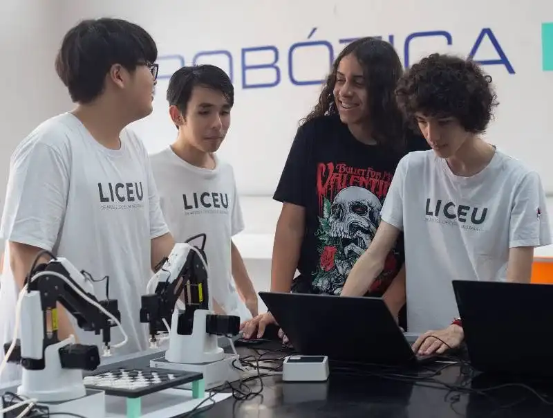 Crianças e adolescentes interagindo em um ambiente de startup, com lousas e protótipos, ilustrando o programa MVP da Lituânia.