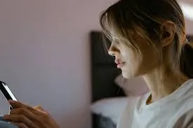 Mulher utilizando um smartphone, com ícones de proteção e segurança em um fundo que representa conectividade e suporte tecnológico.