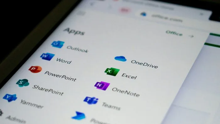 Logotipos do Microsoft Outlook e Microsoft Teams em tela de computador, com símbolos de erro ou falha sobrepostos.