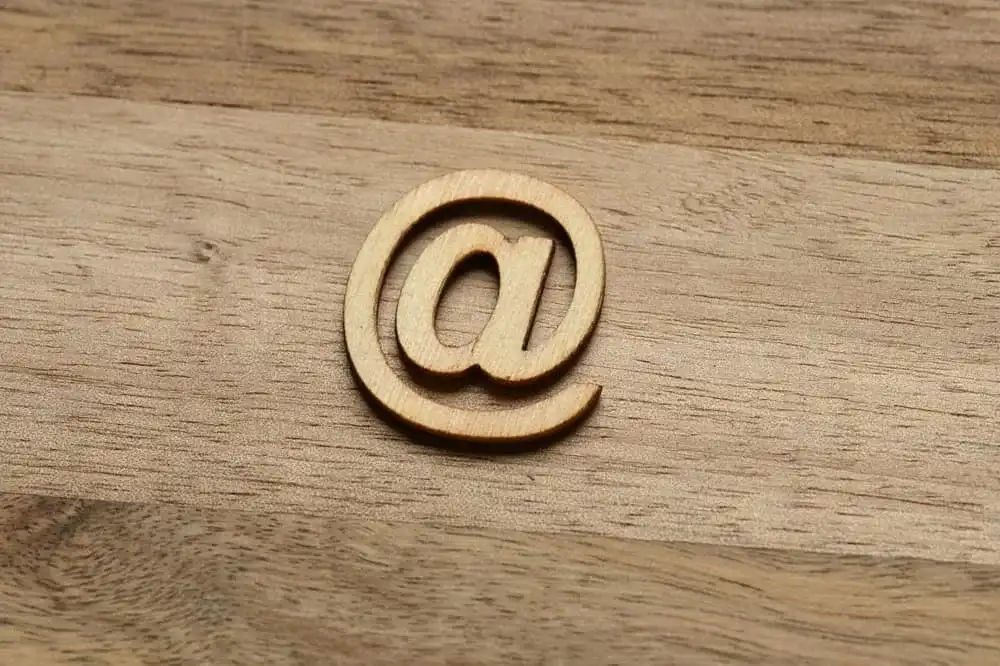 Símbolo arroba com fundo que simula tecnologia e conexões digitais, representando a história e o uso do caractere.