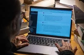 Pessoa digitando em um teclado de computador com elementos digitais de segurança e inteligência artificial flutuando ao redor, simbolizando a interação entre humanos e IA e os riscos cibernéticos