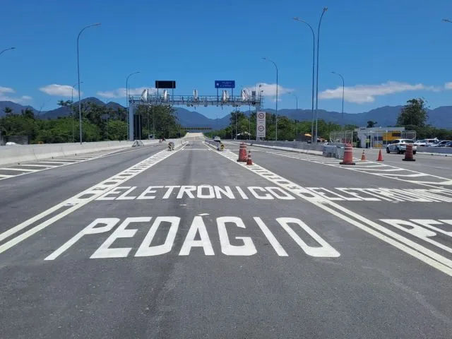 Câmeras de pedágio free flow instaladas em uma rodovia, com carros passando por baixo. A imagem destaca a tecnologia por trás do sistema de cobrança automática e sem cancelas, sob um céu azul.