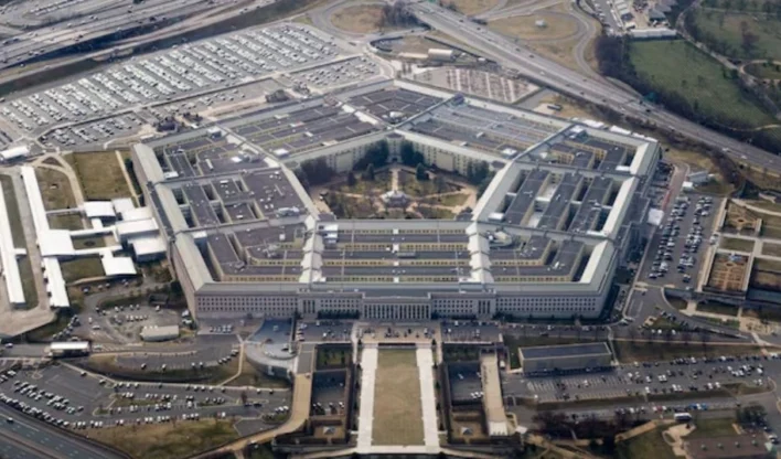 Um soldado em frente a uma tela com elementos de inteligência artificial, simbolizando a interação entre defesa e tecnologia.