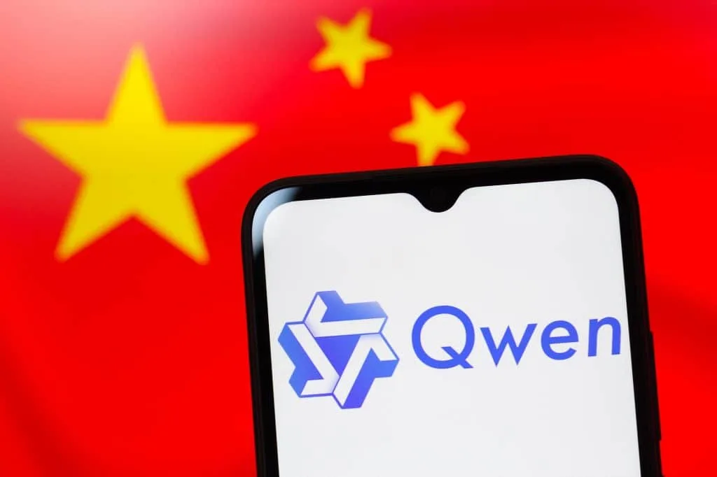 Close-up do logo do Qwen em um celular, com a bandeira da China borrada ao fundo, simbolizando a integração da IA chinesa em veículos.