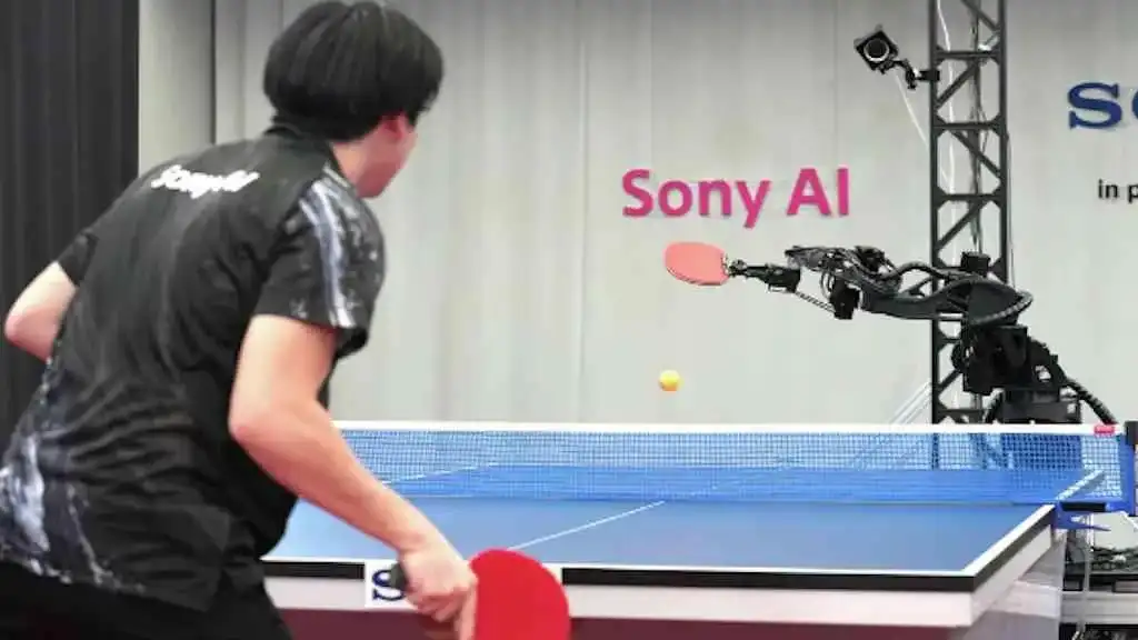 Robô Ace da Sony com raquete de tênis de mesa em posição de jogo, desafiando a percepção humana sobre inteligência artificial.
