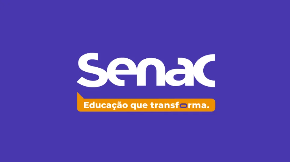 Pessoas em um ambiente de aprendizado tecnológico, olhando para telas de computador e interagindo, simbolizando os cursos oferecidos pelo Senac na área de tecnologia e inovação.