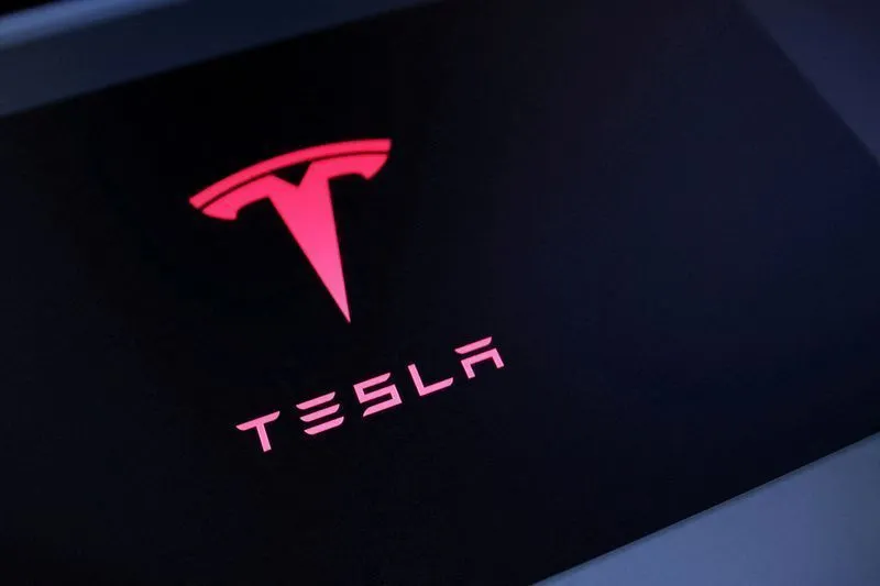 Robô Tesla Optimus ao lado de um carro elétrico Tesla, simbolizando o investimento da empresa em IA e robótica.